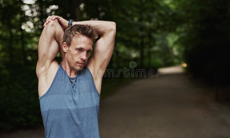 Half Body Shot of an Athletic Young Man Stretching his Arms Behind his Head While in an Outdoor Fitness Training. Half Body Shot of an Athletic Young Man Stretching his Arms Behind his Head While in an Outdoor Fitness Training.