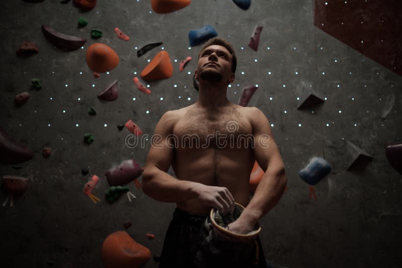 Athletic Man Using Chalk before Climbing in a Bouldering Gym Stock