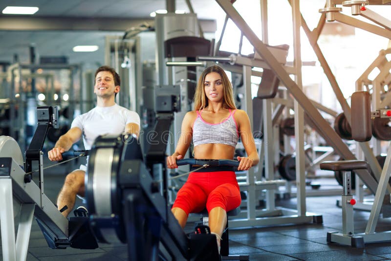 Athletic Man and Woman Training on Row Machine in Gym Stock Image ...