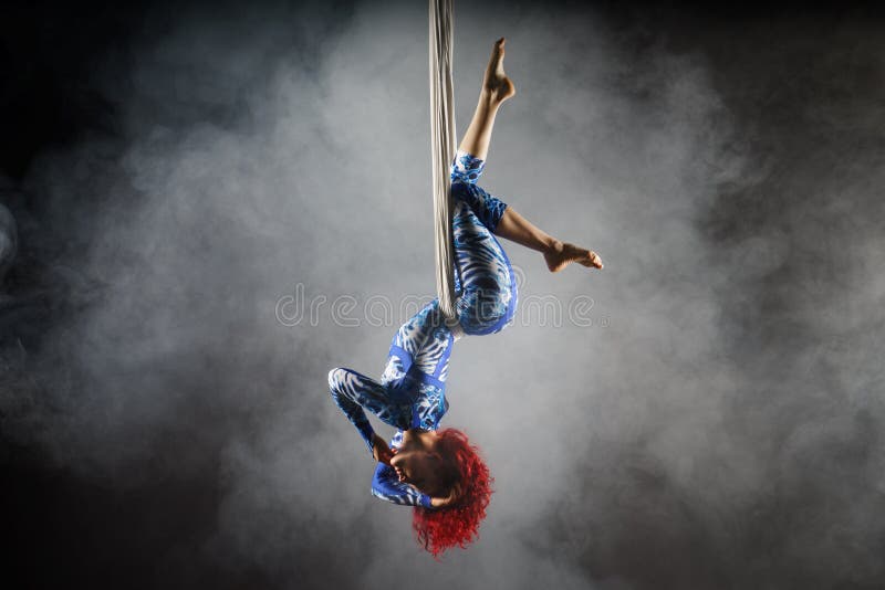 Athletic aerial circus artist with redhead in blue costume making tricks on the aerial silk royalty free stock images Athletic aerial circus artist with redhead in blue costume making tricks on the aerial silk royalty free stock images