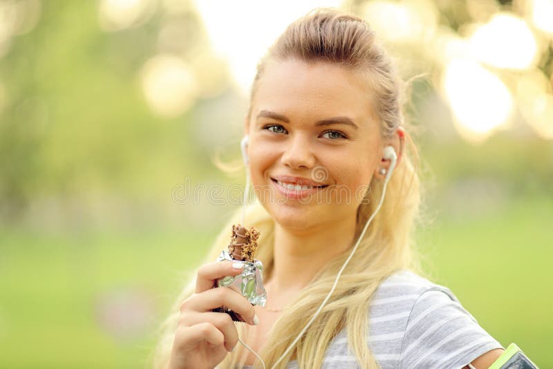 Athletic woman eating a protein bar - Closeup portrait of smiling young sporty girl posing while resting royalty free stock images Athletic woman eating a protein bar - Closeup portrait of smiling young sporty girl posing while resting royalty free stock images