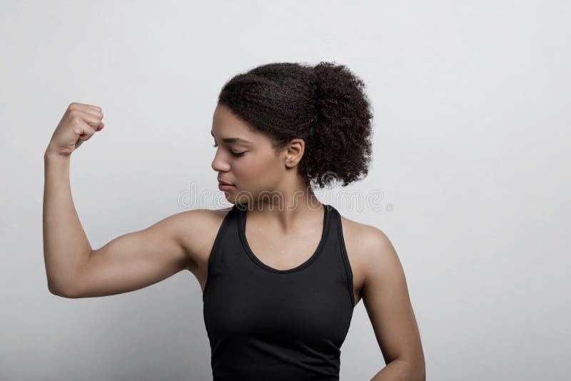 Athletic woman flexing her arm muscle in studio