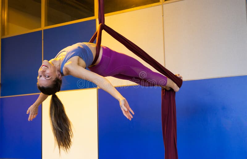 Athletic woman practicing horizontal exercise on aerial silks in studio royalty free stock image
