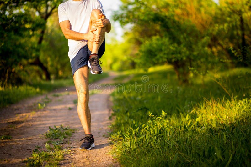 Athletic young man stretchng before run in nature