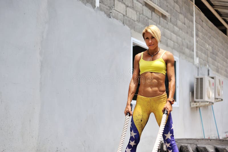 Athletic young woman doing some crossfit exercises with a rope o