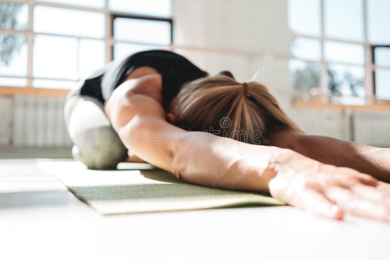Athletickwoman joven que hace ejercicio de la yoga en la estera de la aptitud en el gimnasio soleado blanco morling temprano fotos de archivo Athletickwoman joven que hace ejercicio de la yoga en la estera de la aptitud en el gimnasio soleado blanco morling temprano fotos de archivo