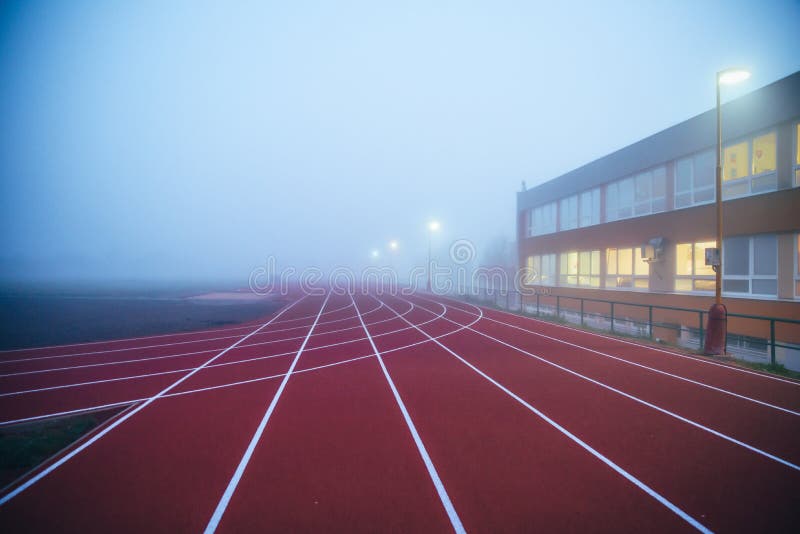 Atletická červená dráha v ranní mlze. Sportovní fotografie