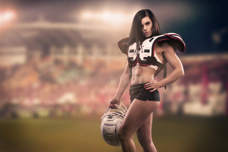 Athletische Frau gekleidet als amerikanischer Fußball-Spieler Reale Uniform, Sturzhelm, Auflagen, Kugel lizenzfreie stockfotografie Athletische Frau gekleidet als amerikanischer Fußball-Spieler Reale Uniform, Sturzhelm, Auflagen, Kugel lizenzfreie stockfotografie