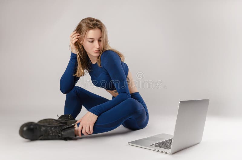 Athletisches Mädchen, das im Studio Durchführung Übungen online auf einem Laptop auf einem weißen Hintergrund darstellt lizenzfreie stockfotografie