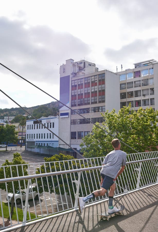 Athlète et homme à skateboard bridge et se déplacer avec vitesse sur la rue extérieure ou des compétences. Voyage photographie stock libre de droits
