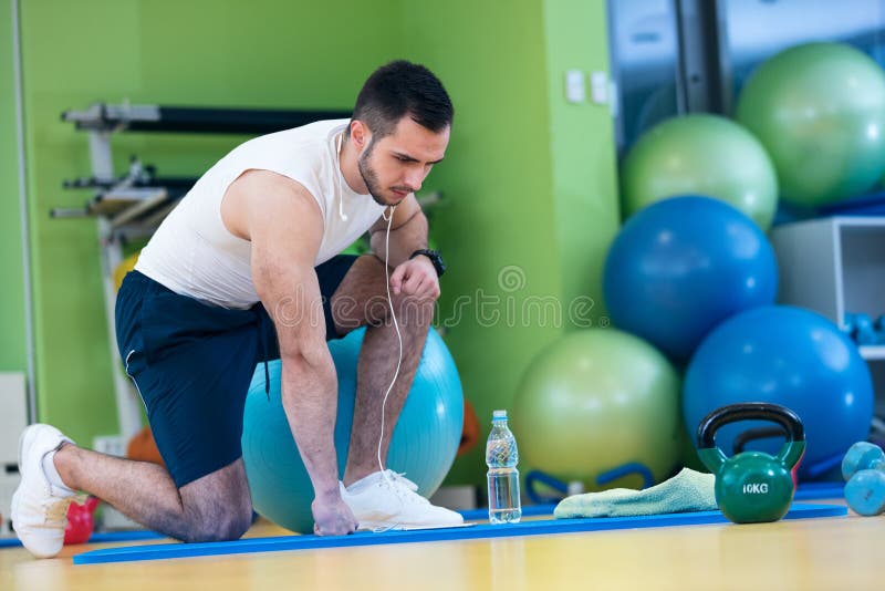 Athlète masculin se mettant à genoux vers le bas par des haltères toweling la sueur de son front photographie stock