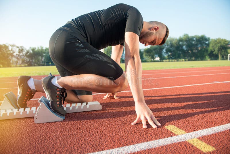 Athlète masculin sur la position de départ à la voie courante d'athlétisme images libres de droits Athlète masculin sur la position de départ à la voie courante d'athlétisme images libres de droits