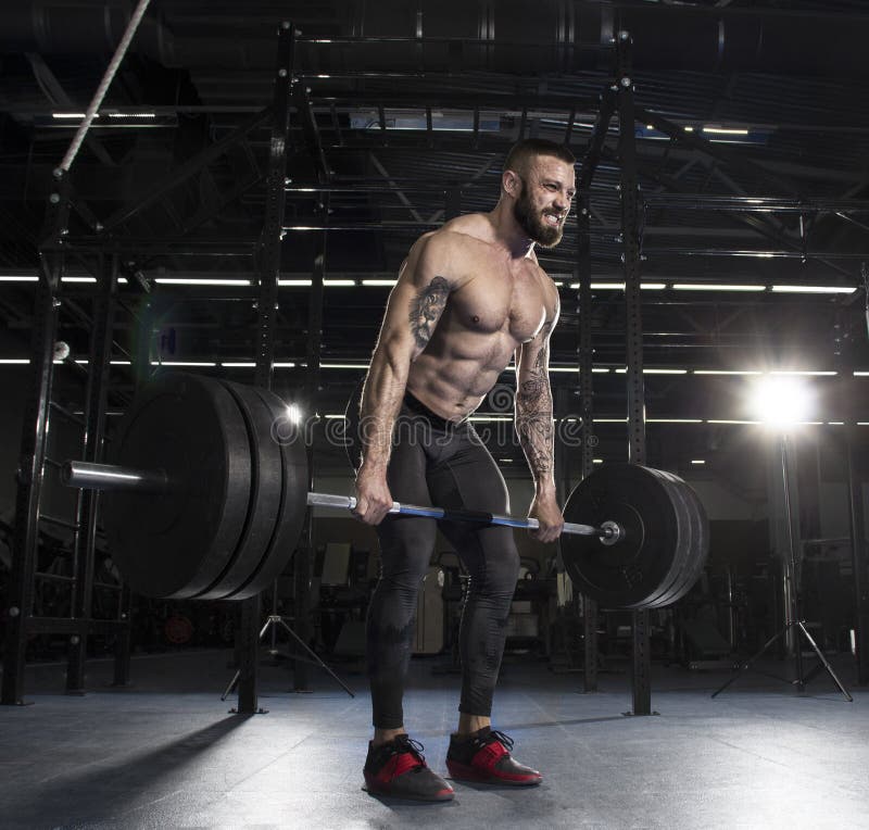 Athlète musculaire attirant faisant l'exercice lourd de deadlift dans le mod photo libre de droits Athlète musculaire attirant faisant l'exercice lourd de deadlift dans le mod photo libre de droits
