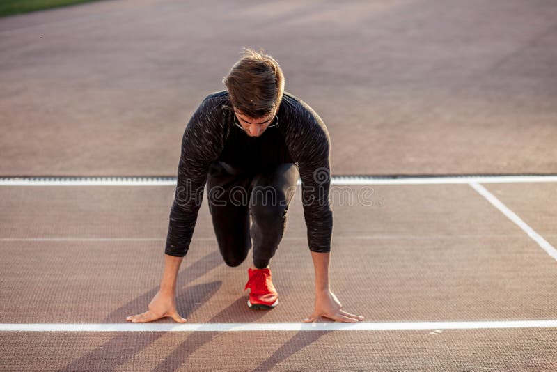 Athlète sur la position de départ à la voie courante Pratique en matière de coureur courue dans le champ de courses de stade photographie stock Athlète sur la position de départ à la voie courante Pratique en matière de coureur courue dans le champ de courses de stade photographie stock