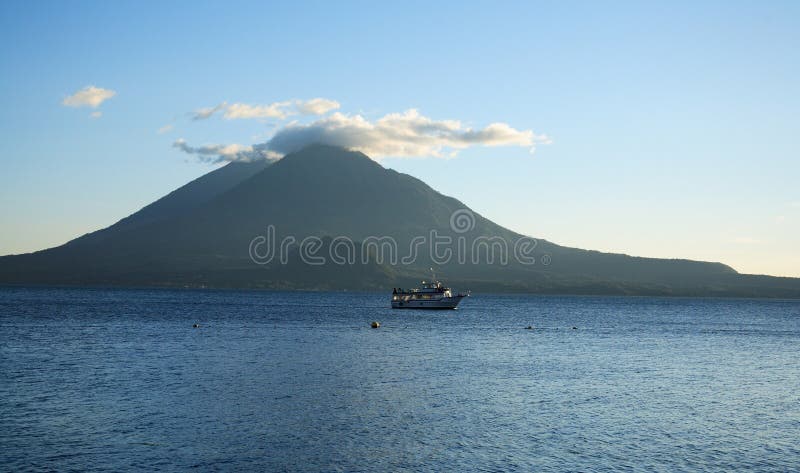 Boat in distance and view of volcanoes in Atitlan Lake, located in Guatemala. Boat in distance and view of volcanoes in Atitlan Lake, located in Guatemala.