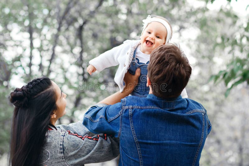 Atividade feliz do ar livre da família, bebê dos aumentos do pai acima, rindo e jogando, mãe das mostras do pai como ao bebê dos foto de stock Atividade feliz do ar livre da família, bebê dos aumentos do pai acima, rindo e jogando, mãe das mostras do pai como ao bebê dos foto de stock