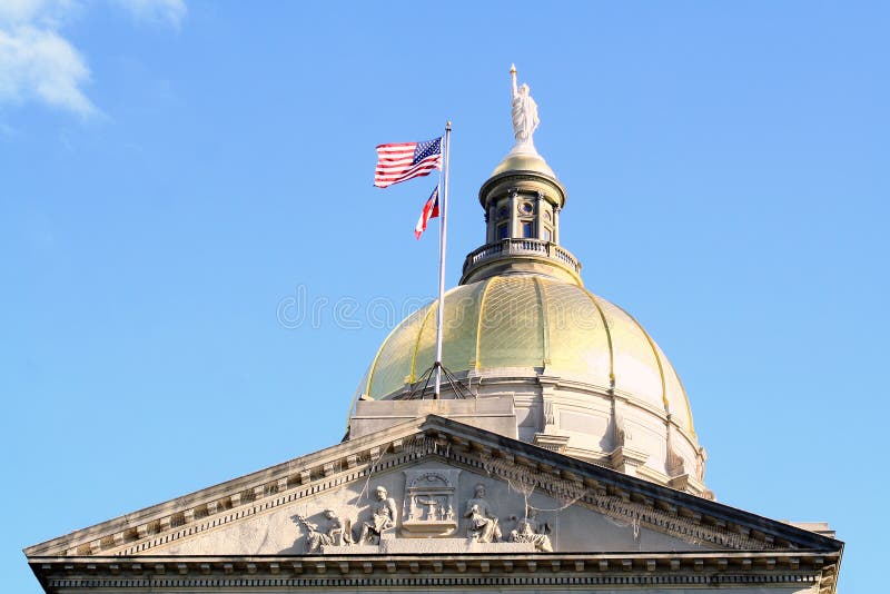 The dome of the capitol building in Atlanta, Georgia, USA. An American flag waves in the breeze and relief sculpture can ve seen near the peak of the building. The dome of the capitol building in Atlanta, Georgia, USA. An American flag waves in the breeze and relief sculpture can ve seen near the peak of the building.