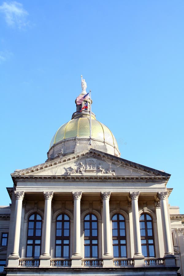 The dome of the capitol building in Atlanta, Georgia, USA. An American flag waves in the breeze and relief sculpture can ve seen near the peak of the building. The dome of the capitol building in Atlanta, Georgia, USA. An American flag waves in the breeze and relief sculpture can ve seen near the peak of the building.