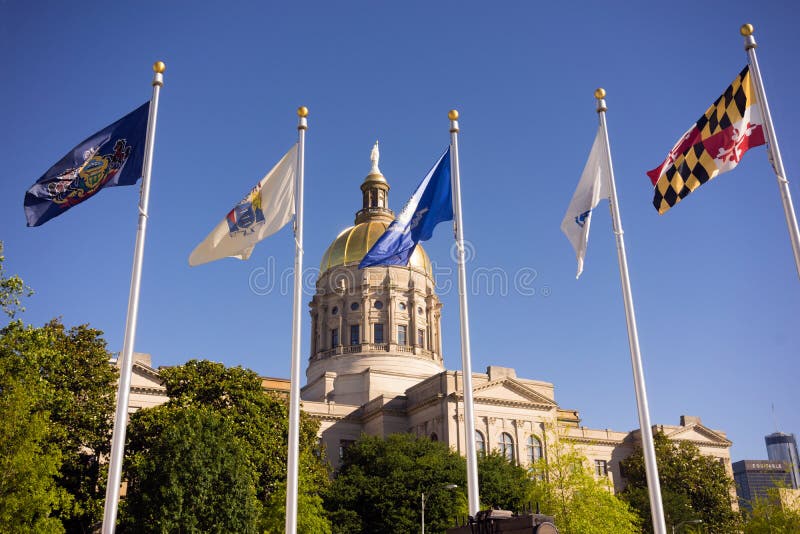 The golden capital dome stands out against a blue sky in Atlanta flags waving. The golden capital dome stands out against a blue sky in Atlanta flags waving