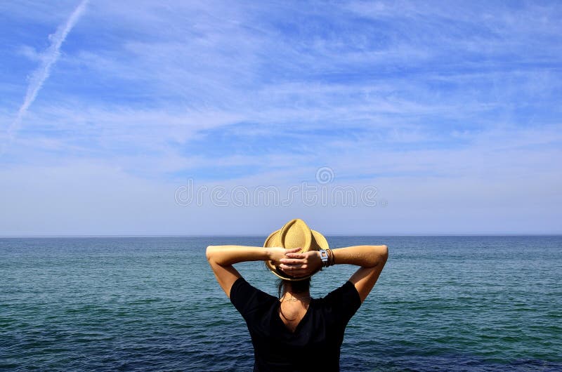 A young woman with raised hands looking at the Atlantic ocean. A young woman with raised hands looking at the Atlantic ocean