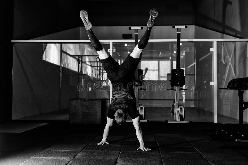 Atleta che cammina sulle sue mani che stanno sottosopra nella palestra Concetto di stile di vita di allenamento Ritratto completo fotografia stock Atleta che cammina sulle sue mani che stanno sottosopra nella palestra Concetto di stile di vita di allenamento Ritratto completo fotografia stock