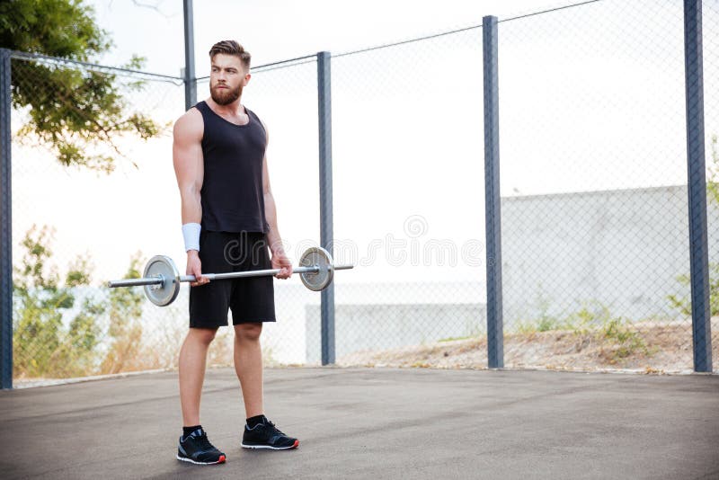 Atleta concentrado del hombre joven que se resuelve con el barbell foto de archivo libre de regalías Atleta concentrado del hombre joven que se resuelve con el barbell foto de archivo libre de regalías