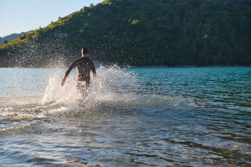 Atleta de triatlón iniciando entrenamiento de natación en el lago foto de archivo
