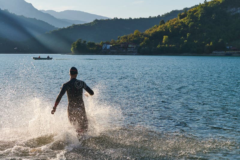 Atleta de triatlón iniciando entrenamiento de natación en el lago imagen de archivo
