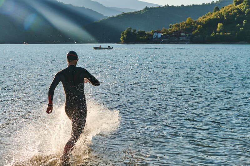 Atleta de triatlón iniciando entrenamiento de natación en el lago foto de archivo