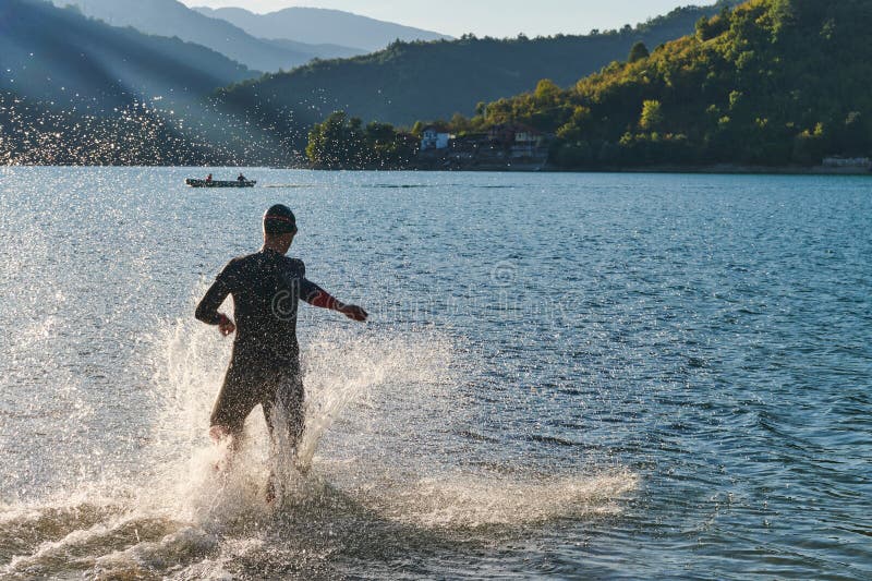 Atleta de triatlón iniciando entrenamiento de natación en el lago fotografía de archivo
