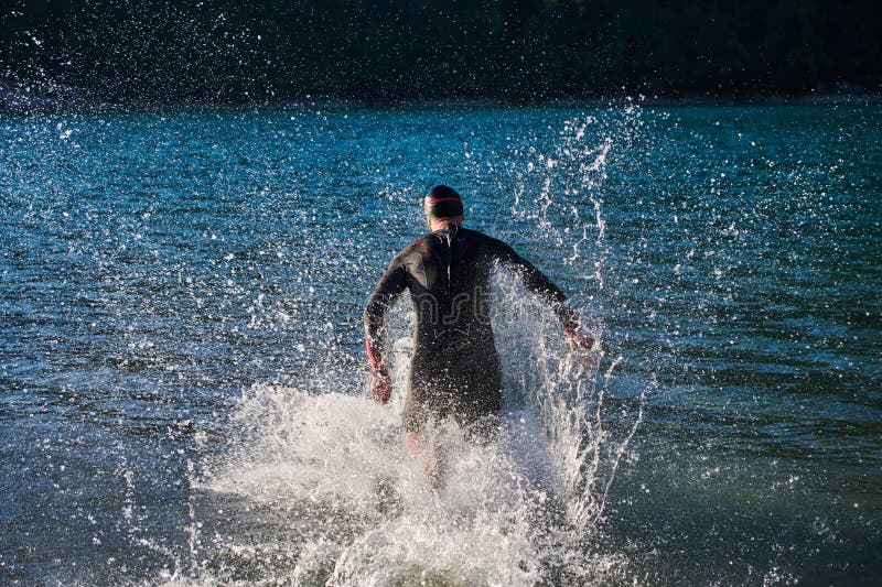 Atleta de triatlón iniciando entrenamiento de natación en el lago fotografía de archivo libre de regalías
