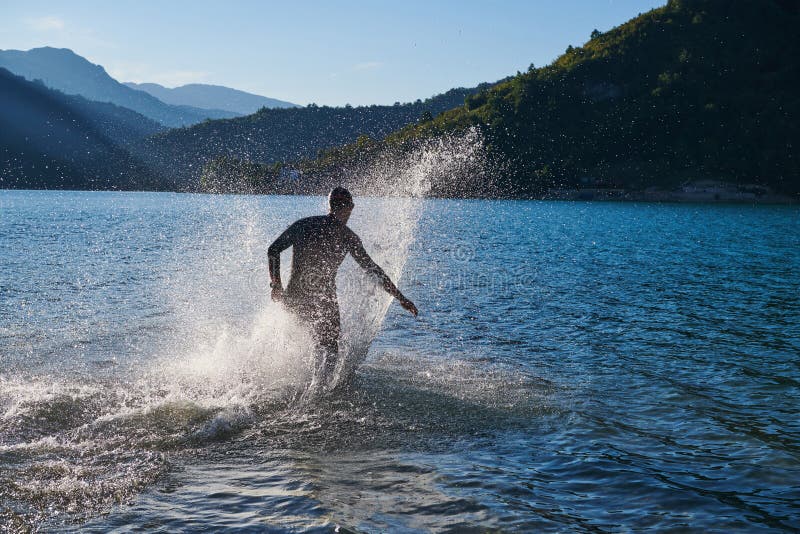 Atleta de triatlón iniciando entrenamiento de natación en el lago imagenes de archivo