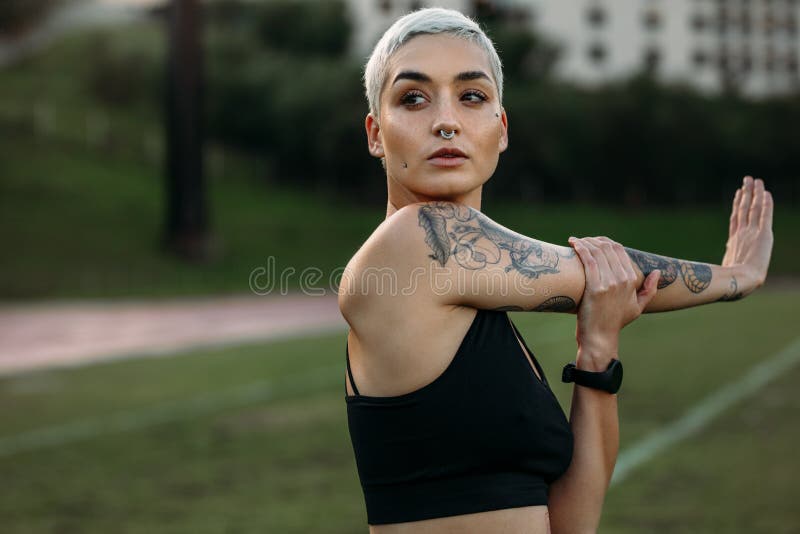 Atleta fêmea que faz o exercício que estica seu braço imagens de stock Atleta fêmea que faz o exercício que estica seu braço imagens de stock