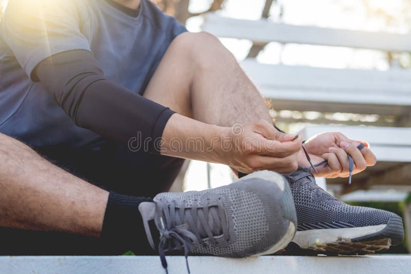 Male athlete tying shoe laces in minimalistic barefoot sneakers getting ready for training. Sport workout and healthy lifestyle concept. Male athlete tying shoe laces in minimalistic barefoot sneakers getting ready for training. Sport workout and healthy lifestyle concept