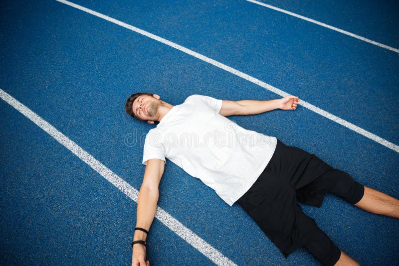 Atleta maschio stanco che riposa dopo avere corso mentre trovandosi sulla pista fotografie stock libere da diritti Atleta maschio stanco che riposa dopo avere corso mentre trovandosi sulla pista fotografie stock libere da diritti