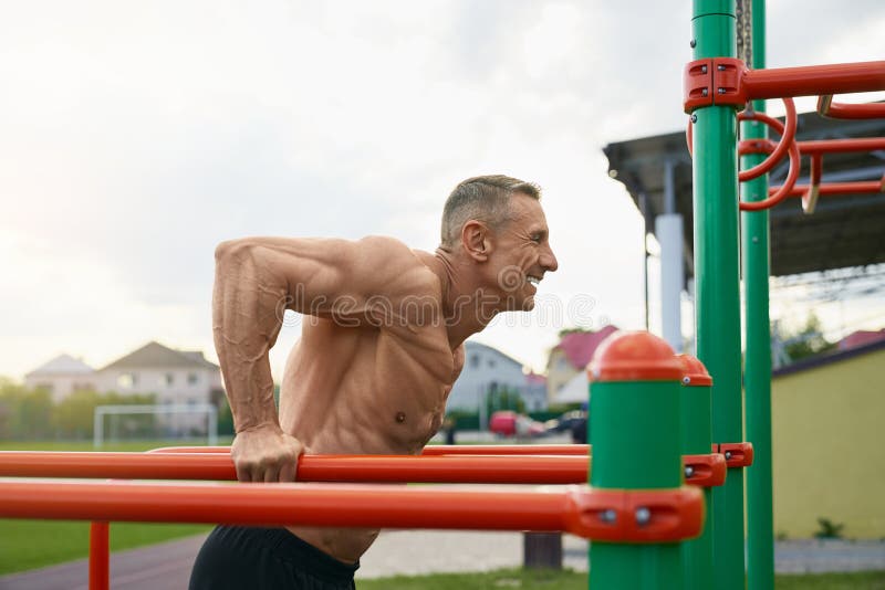 Atleta masculino haciendo ejercicios de armas en barras paralelas fotos de archivo