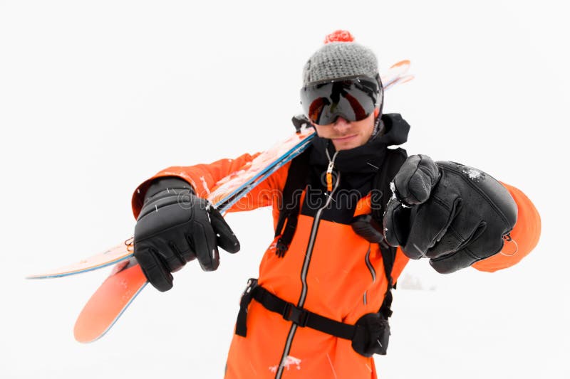Atleta professionista dello sciatore in un cappello tricottato e vestito nero arancio con una passamontagna nera con gli sci sui immagine stock libera da diritti Atleta professionista dello sciatore in un cappello tricottato e vestito nero arancio con una passamontagna nera con gli sci sui immagine stock libera da diritti