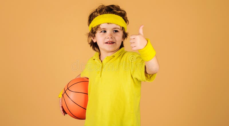 Gioco di allenamento di basket. Bambino sorridente con palla da basket che  mostra il pollice in