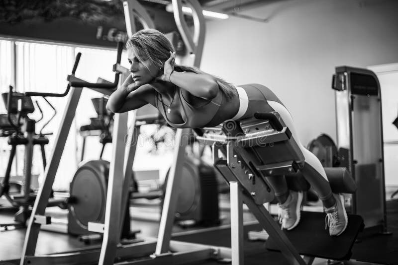 Atletische jonge vrouw die hyperextensie in de gymnastiek doen De achter en buikspieren van de vrouwenverbuiging stock fotografie Atletische jonge vrouw die hyperextensie in de gymnastiek doen De achter en buikspieren van de vrouwenverbuiging stock fotografie