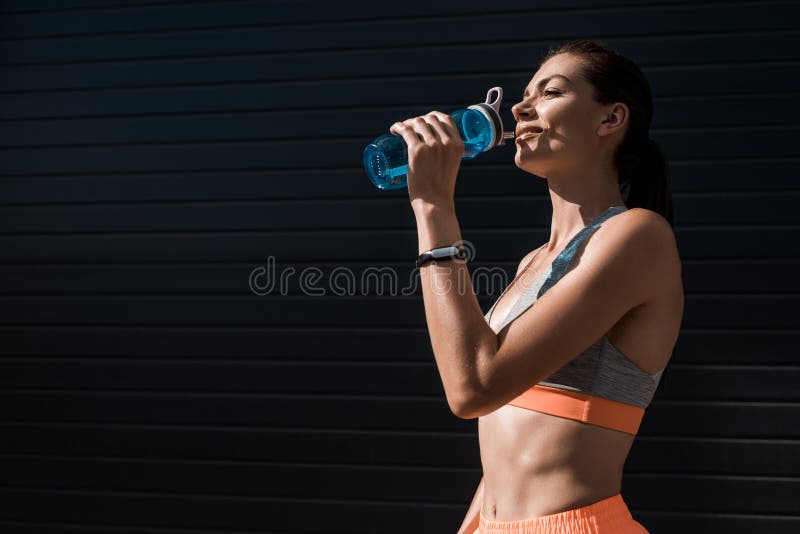 atletische vrouw met het drinkwater van de geschiktheidsdrijver van
