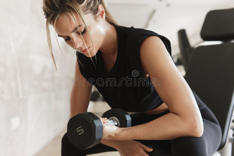 Atletisk kvinna som tränar bicepkurl med en propp på gymmet. Unga friska kvinnor som tränar bicepkurl med en propp på gymmet