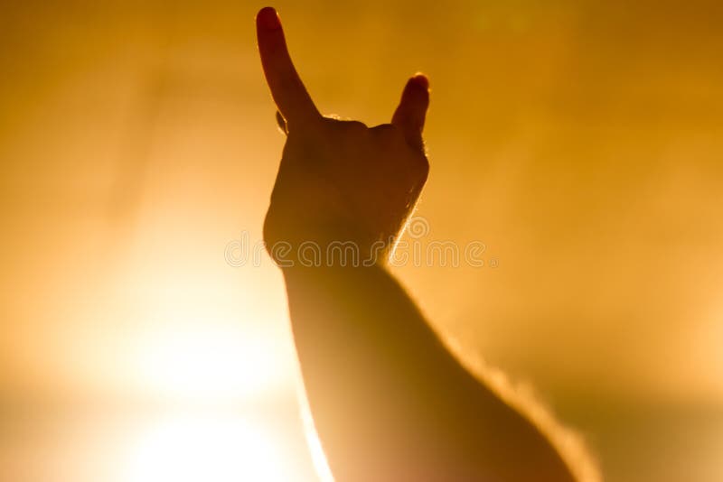 Atmosfera magica al concerto - gesto simbolico, mano sollevata sul concerto di musica nel riflettore giallo immagine stock libera da diritti Atmosfera magica al concerto - gesto simbolico, mano sollevata sul concerto di musica nel riflettore giallo immagine stock libera da diritti