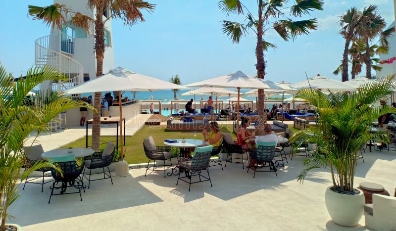 Kuta, Indonesia - 15th October 2019; Tourists have a good time and relax under white umbrellas in the Cafe Del Mar Bali beach club on a sunny day. Kuta, Indonesia - 15th October 2019; Tourists have a good time and relax under white umbrellas in the Cafe Del Mar Bali beach club on a sunny day