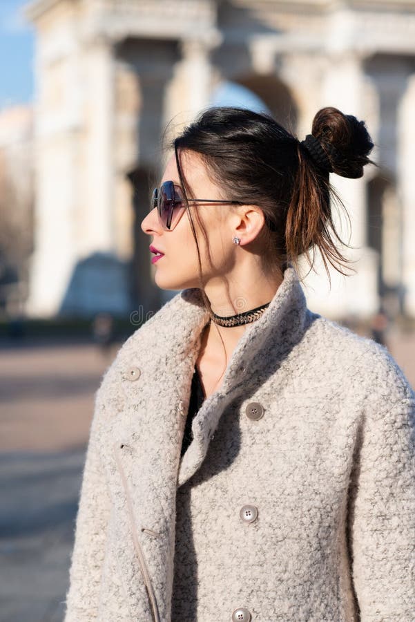 Atractiva Joven Mujer Que Usa Un Abrigo Gris Con El Oscuro Largo Lentes De Sol Posando Al Aire Libre En Las Calles De Milán Imagen de archivo - Imagen