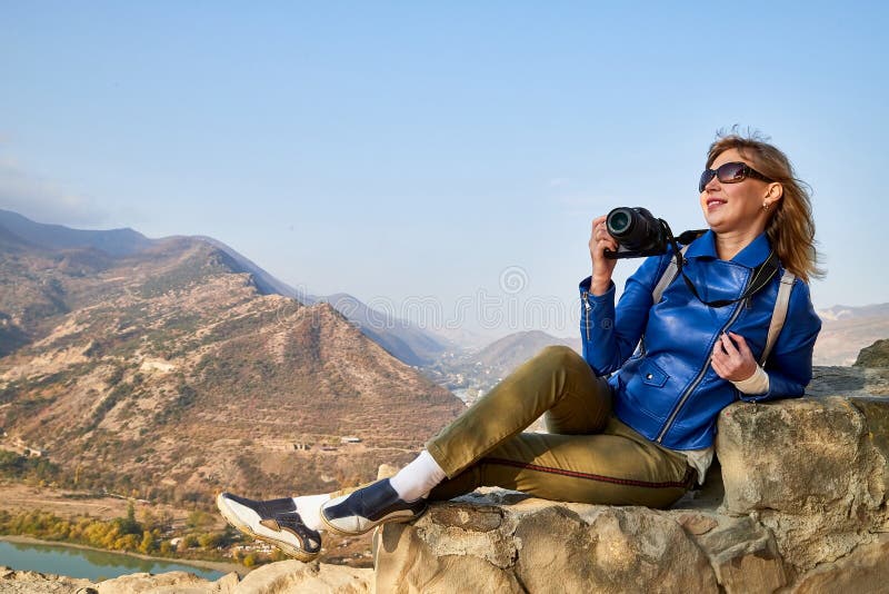 Atractiva y hermosa joven que es mujer viajera fotógrafa sosteniendo una moderna cámara espejo en las manos al aire libre foto de archivo