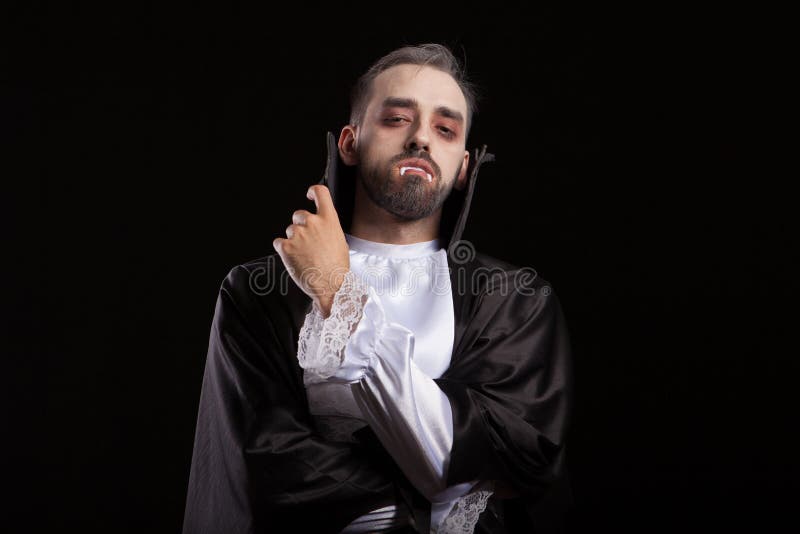 Homem bonito vestido com uma fantasia de drácula para o halloween. vampiro  atraente com velas