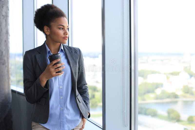 Attractive african american business woman smiling while standing in the office. Attractive african american business woman smiling while standing in the office.