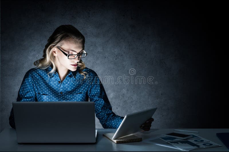 Atrakcyjna blondynka pracuje na laptopie w ciemnym biurze Mieszani środki zdjęcia stock Atrakcyjna blondynka pracuje na laptopie w ciemnym biurze Mieszani środki zdjęcia stock