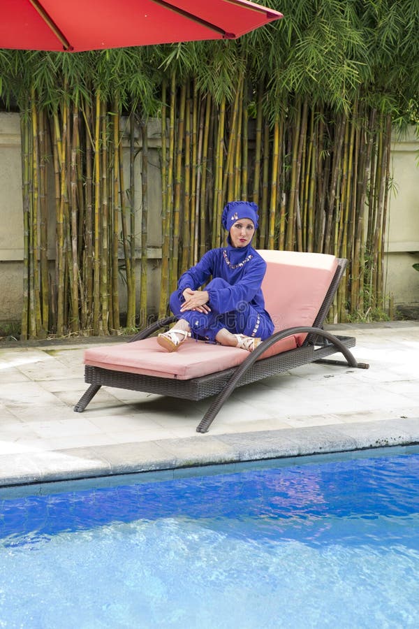 Atrakcyjna kobieta w Muzułmańskim swimwear burkini na plażowym deski łóżku blisko basenu obraz royalty free Atrakcyjna kobieta w Muzułmańskim swimwear burkini na plażowym deski łóżku blisko basenu obraz royalty free