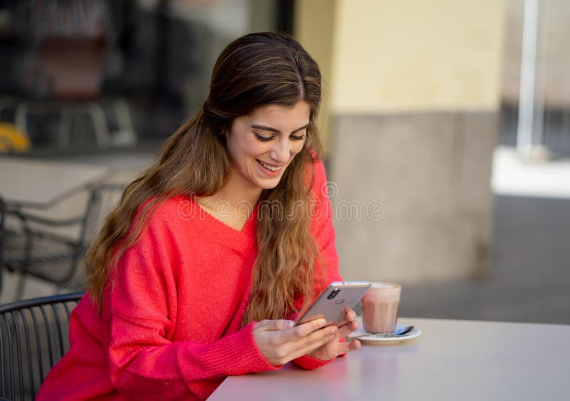 Atrakcyjna młoda kobieta używa mądrze telefonu komórkowego datowanie app w sklepu z kawą outside tarasie zdjęcie royalty free Atrakcyjna młoda kobieta używa mądrze telefonu komórkowego datowanie app w sklepu z kawą outside tarasie zdjęcie royalty free